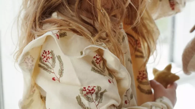 Detské šaty s vianočným motívom, smotanové s potlačou imela a jarabiny, v ramenách všité volániky, prestrihnuté v páse s naberanou sukňou.